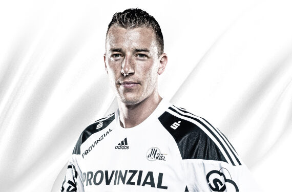Ein männlicher Sportler in einem weiß-schwarzen Sporttrikot mit der Aufschrift PROVINZIAL auf der Vorderseite steht vor einem weißen Hintergrund und schaut mit neutralem Blick in die Kamera. Das Adidas-Logo und andere Sponsoren sind auf dem Trikot zu sehen.