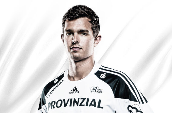 Ein junger Mann in einem weiß-schwarzen Sporttrikot mit PROVINZIAL- und Adidas-Logos steht vor einem weißen Hintergrund. Das Trikot hat ein Vereinsabzeichen auf der Brust und gestreifte Schultern.