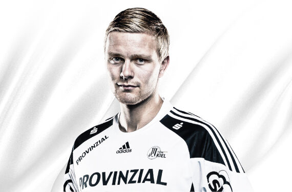 Ein männlicher Sportler mit kurzen blonden Haaren, der ein weißes und schwarzes Sporttrikot mit dem Wort PROVINZIAL und verschiedenen Logos trägt, steht vor einem weißen Hintergrund.