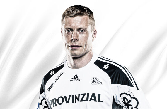 Ein männlicher Handballspieler in einem weiß-schwarzen Trikot mit der Aufschrift Provinzial auf der Vorderseite steht vor einem weißen Hintergrund. Auf dem Trikot sind die Logos von Adidas und dem THW Kiel abgebildet.