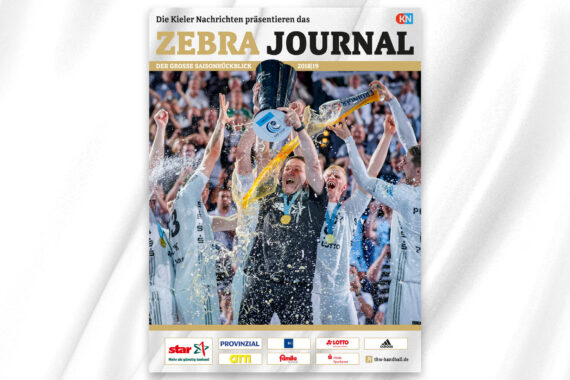 Eine jubelnde Sportmannschaft feiert auf einer Bühne, verspritzt Champagner und hebt eine Trophäe. Auf der Titelseite des Magazins steht "Zebra Journal", und im Hintergrund jubeln aufgeregte Spieler in weißen Trikots.