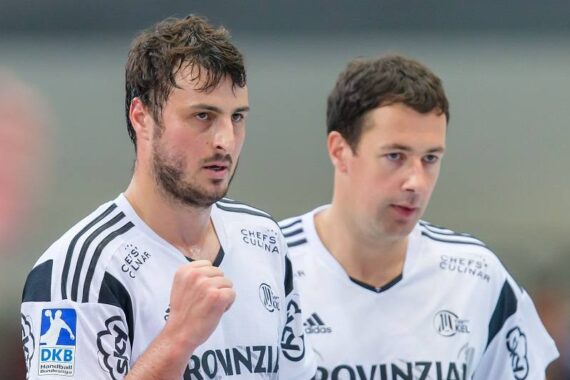 Zwei männliche Handballspieler in weißen Trikots mit der Aufschrift PROVINZIAL auf der Vorderseite stehen nebeneinander, einer mit einer geballten Faust. Beide wirken konzentriert während eines Spiels. Auf dem Ärmel ist das Logo der DKB Handball-Bundesliga zu sehen.