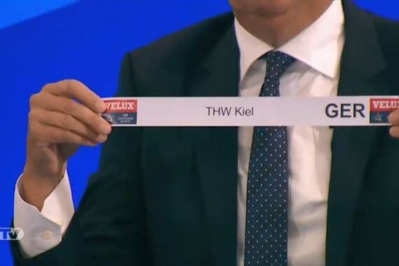 Eine Person im Anzug hält einen Papierstreifen mit der Aufschrift THW Kiel und den Logos GER und VELUX in der Hand, wahrscheinlich während einer im Fernsehen übertragenen Sportauslosung. Das efitv-Logo erscheint in der unteren linken Ecke.