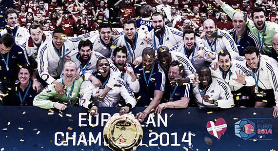 Ein jubelndes Team in weiß-blauen Trikots feiert den Gewinn der EHF-Europameisterschaft 2014, versammelt um eine Trophäe, auf die goldenes Konfetti fällt, umgeben von jubelnden Fans und mit Medaillen in der Hand.