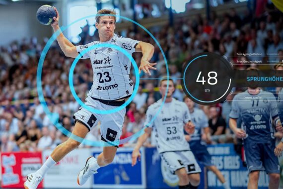 Ein Handballspieler in einem weißen Trikot springt, um den Ball zu werfen, wobei eine digitale Grafik eine Sprunghöhe von 48 cm und Statistiken einblendet. Eine Menschenmenge beobachtet das Geschehen im Hintergrund.