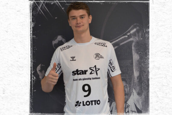 Ein junger Mann in einem weißen Sporttrikot mit der Nummer 9 steht vor einem schwarz-weißen Hintergrund, macht eine Daumen-hoch-Geste und schaut in die Kamera. Auf dem Trikot sind mehrere Sponsorenlogos zu sehen.