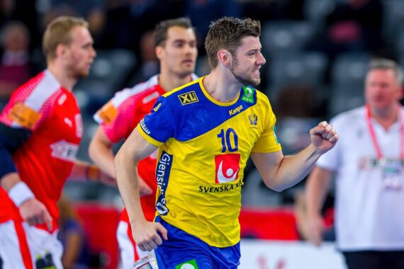 Ein männlicher Handballspieler in einem gelb-blauen Trikot mit der Nummer 10 feiert während eines Spiels. Im Hintergrund sind zwei Gegner in roten Trikots und eine weitere Person in Weiß zu sehen. Die Szene findet in einer Halle statt.