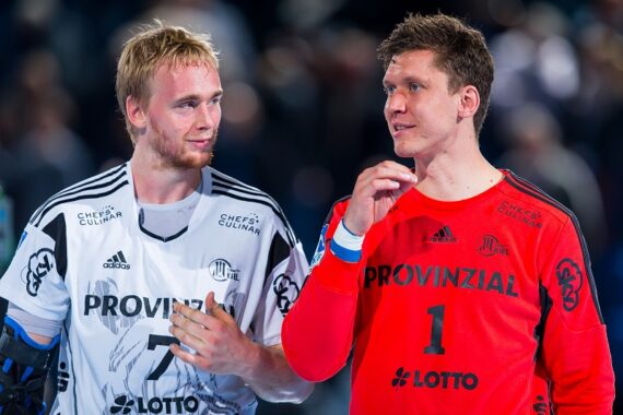 Zwei männliche Handballspieler in weißen und roten Trikots stehen zusammen, lächeln und unterhalten sich nach einem Spiel. Der Spieler in Rot trägt die Nummer 1 und auf beiden Trikots steht vorne PROVINZIAL.