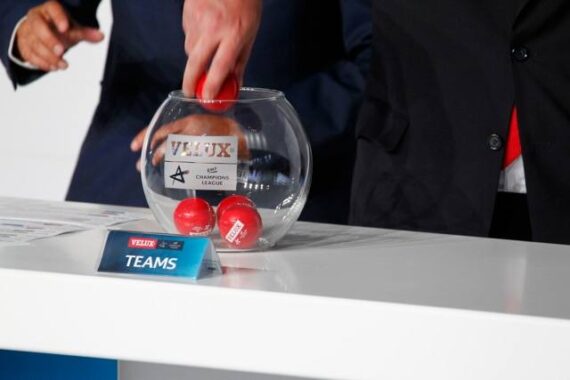 Zwei Personen in Anzügen ziehen während einer Mannschaftsauswahl rote Kugeln aus einer Glasschale mit der Aufschrift VELUX EHF Champions League. Auf einem Schild auf dem Tisch steht TEAMS.