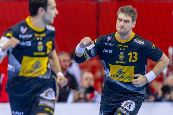 Zwei männliche Handballspieler in dunkelblauen Spanien-Trikots laufen auf das Spielfeld, einer mit der Nummer 13 ballt jubelnd die Faust. Der Hintergrund zeigt eine rote Wand und unscharfe Zuschauer.