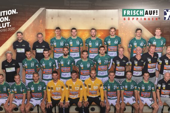 Mannschaftsfoto des Handballvereins Frisch Auf Göppingen der Saison 2019/2020; Spieler und Mitarbeiter in grünen Trikots posieren in einer Reihe mit Sponsorenlogos und Bannern, darunter "Tradition. Emotion. Herzblut." auf der linken Seite.