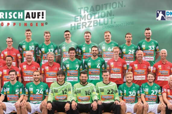 Gruppenfoto der Frisch Auf! Göppinger Handballer und Mitarbeiter in grünen, roten und blaugrünen Trikots posieren vor einem grünen Hintergrund mit Sponsorenlogos und dem Text TRADITION. EMOTION. HERZBLUT. SAISON 2017/2018.