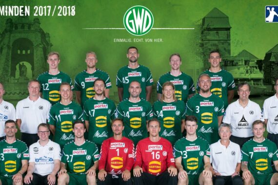 Mannschaftsfoto des Handballkaders 2017/2018 von GWD Minden mit Spielern und Betreuern in grün-weißen Trikots in Dreierreihen mit einem Wahrzeichen der Stadt im Hintergrund und Sponsorenlogos im Bild.