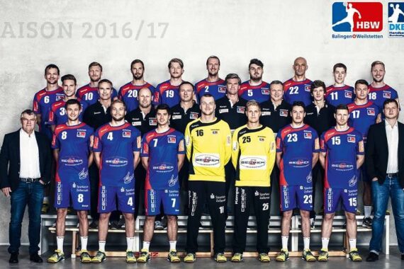 Gruppenfoto der Handballmannschaft des HBW Balingen-Weilstetten aus der Saison 2016/17. Spieler und Betreuer posieren in drei Reihen, alle in Mannschaftstrikots oder Anzügen, vor einem grauen Hintergrund.