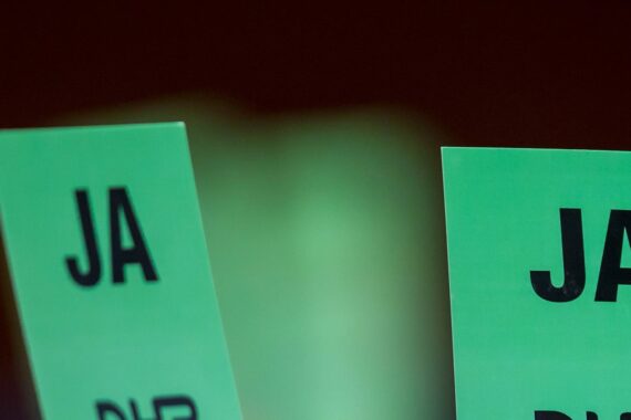 Zwei grüne Karten mit dem Wort JA in fetten schwarzen Buchstaben, die vor einem dunklen Hintergrund gehalten werden.