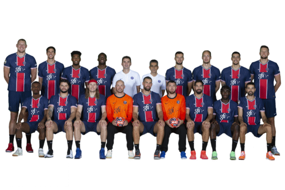 Eine Gruppe von 17 Männern in passenden blauen und roten Sportuniformen posiert für ein Mannschaftsfoto. Vier Männer in orangefarbenen Trikots sitzen vorne und halten Handbälle vor einem weißen Hintergrund.