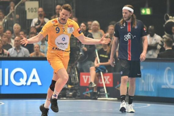 Ein Handballspieler in einem gelben Trikot jubelt mit ausgestreckten Armen auf dem Spielfeld, während ein Spieler in einem dunkelblauen Trikot zuschaut; im Hintergrund sieht ein Publikum auf der Tribüne zu.