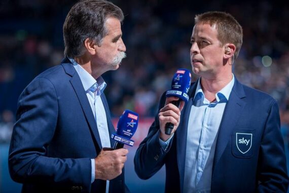 Zwei männliche Sportkommentatoren in blauen Blazern halten Mikrofone mit Sky Sports-Logos in der Hand und sprechen vor einem verschwommenen Publikum bei einer Hallenveranstaltung miteinander.