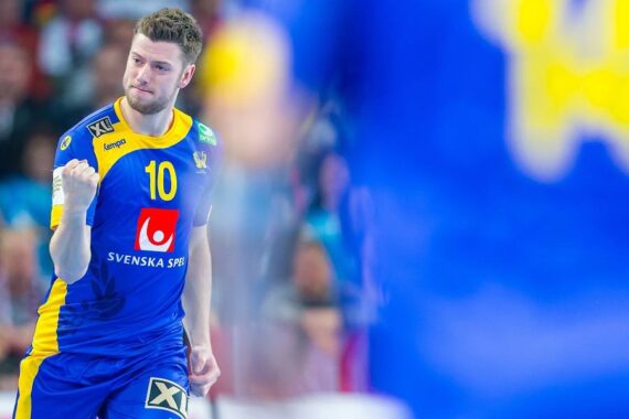 Ein männlicher Sportler in einem blau-gelben Trikot mit der Nummer 10 ballt während eines Handballspiels jubelnd die Faust. Der Hintergrund ist unscharf und hebt den Ausdruck und die Bewegung des Spielers hervor.