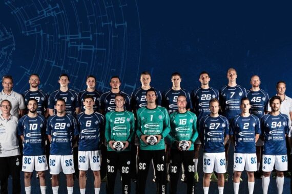 Eine Herrenhandballmannschaft in blau-weißen Trikots steht in zwei Reihen mit Trainern und Betreuern für ein Gruppenfoto vor einem dunkelblauen, digital gestalteten Hintergrund.