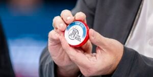 Eine Person hält bei der THW Kiel EHF European League Saison 2024/2025 Finals Auslosung ein rot-weißes rundes Objekt mit dem THW Kiel-Logo, das ein stilisiertes Zebra und Sterne zeigt, zwischen ihren Händen.