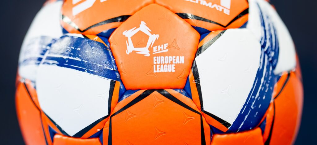 Nahaufnahme eines orange-weiß-blauen Handballs mit dem Logo der EHF-Europa-Liga auf einem der Felder.