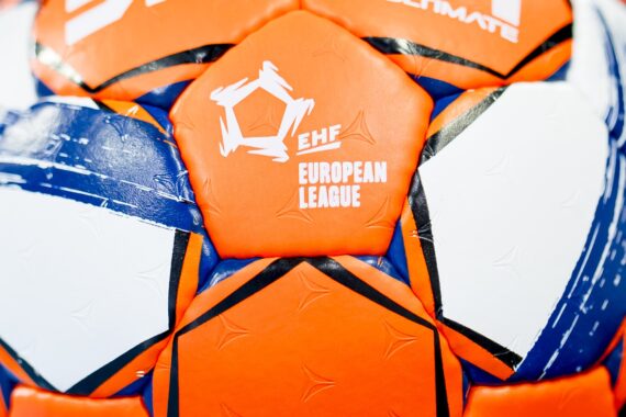 Nahaufnahme eines orange-weiß-blauen Handballs mit dem Logo der EHF-Europa-Liga auf einem der Felder.