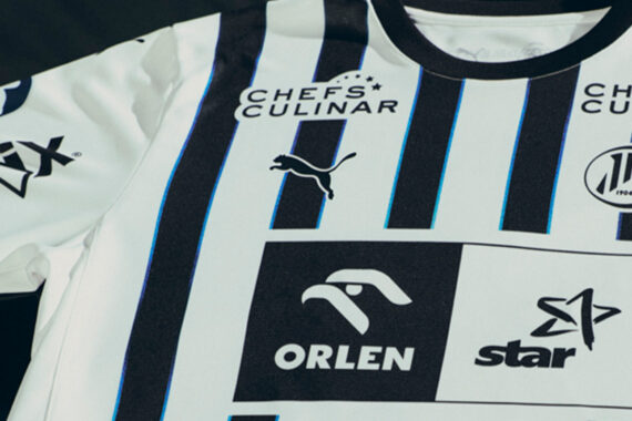 Ein weißes Sporttrikot mit vertikalen schwarzen Streifen, auf denen die Logos von Puma, Chefs Culinar, Haix, ORLEN, star und das Abzeichen des Handballvereins THW Kiel abgebildet sind.