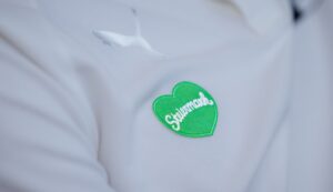 Nahaufnahme eines weißen Hemds mit einem weißen Puma-Logo und einem grünen herzförmigen Aufnäher mit der Aufschrift Steiermark in weißer Schrift.