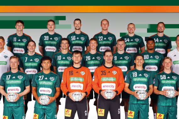 Eine Handballmannschaft der Männer posiert für ein Gruppenfoto in grünen Trikots mit Mitarbeitern in weißen Hemden, die Handbälle halten, vor einem Hintergrund mit grünen und orangefarbenen Streifen.