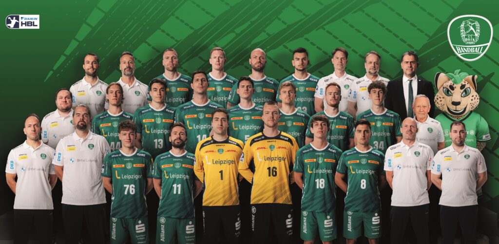 ScDHfK-Handball-Mannschaftsplakat-RR-25_26-A4.indd Gruppenfoto einer Herrenhandballmannschaft in grünen Trikots, mit zwei Spielern in gelben Torwarttrikots, Trainern und Betreuern in weißen Hemden und einem Leopardenmaskottchen, die alle vor einem grünen Hintergrund mit Mannschaftslogos posieren.