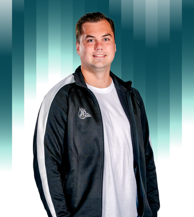 Ein Mann in einer schwarz-weißen Jacke mit Reißverschluss über einem weißen T-Shirt steht lächelnd vor einem blauen und weißen Hintergrund mit vertikalem Farbverlauf.