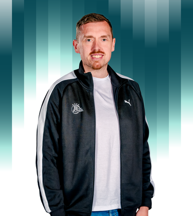 THWKiel-Tim_Schlichting Ein Mann mit kurzen Haaren und gestutztem Bart trägt eine schwarz-weiße Puma-Jacke über einem weißen T-Shirt und steht vor einem Hintergrund mit blauem Farbverlauf und vertikalen Balken.