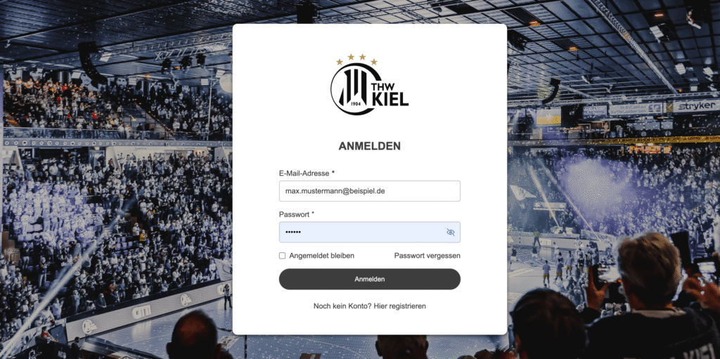 25_PM_SSO_Einwahl Login-Seite für den THW Kiel vor dem unscharfen Hintergrund einer mit Zuschauern gefüllten Handballhalle. Das Formular fragt nach E-Mail-Adresse und Passwort, mit den Optionen, eingeloggt zu bleiben oder das Passwort wiederherzustellen.