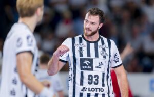 Ein Handballspieler des THW Kiel in einem schwarz-weiß gestreiften Trikot mit der Nummer 93 ballt während eines Spiels jubelnd die Faust, während ein anderer Spieler teilweise zu sehen ist - und fängt damit die Spannung der EHF European League Handball Saison 2025/2026 ein.