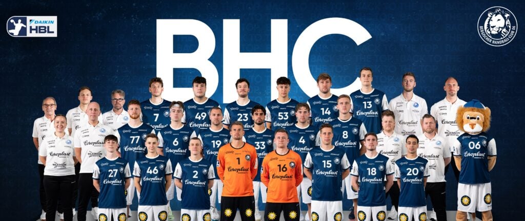 Eine Handballmannschaft posiert für ein Gruppenfoto in blau-weißen Trikots und steht in einer Reihe mit Trainern und Betreuern. Rechts steht eine Person in einem Löwenmaskottchenkostüm. Hinter ihnen steht in großen weißen Buchstaben BHC.