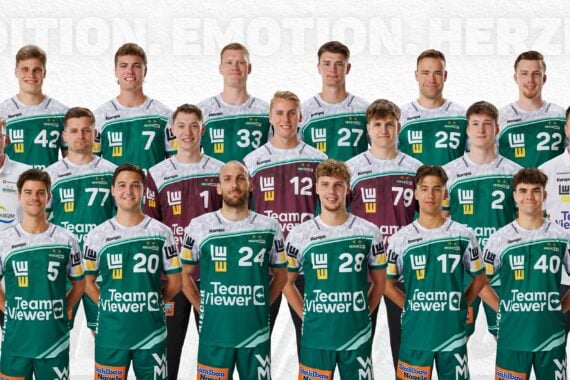 Eine Herren-Volleyballmannschaft und ihre Betreuer posieren für ein offizielles Gruppenfoto. Alle tragen grüne, weiße oder kastanienbraune Trikots mit Sponsorenlogos und stehen oder knien in Reihen vor einem weißen Hintergrund.