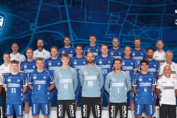 Eine Herren-Handballmannschaft posiert in blauen und weißen Trikots mit Trainern und Mitarbeitern, die auf beiden Seiten stehen. Im Hintergrund sind eine blaue Landkarte und das Mannschaftslogo zu sehen. Der Text "Saison 25/26" erscheint in der oberen rechten Ecke.