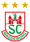Das Logo des SC Magdeburg zeigt ein rot-weißes Schild mit zwei Türmen und einer Figur in der Mitte oben, grünen SC-Buchstaben, MAGDEBURG unten und drei goldenen Sternen über dem Schild.