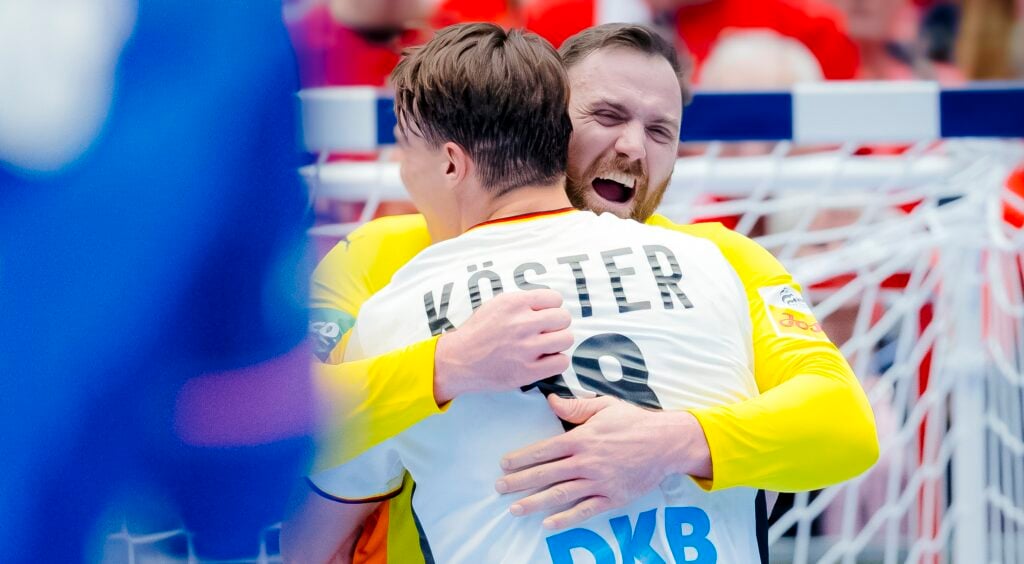 HANDBALL-EM 2026: Deutschland - Frankreich Zwei männliche Handballspieler in weißen Trikots umarmen sich und feiern fröhlich auf dem Spielfeld vor einem Tornetz, wobei der Name Köster