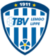 Ein blau-weißes schildförmiges Logo mit 1911 oben, zwei gelben Sternen, einer sechseckigen Kugel, dem Text TBV LEMGO LIPPE und einer blauen Blume mit gelber Mitte unten.