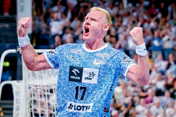 Ein Handballspieler in einem blau-weißen Trikot mit der Nummer 17 feiert leidenschaftlich mit geballten Fäusten und offenem Mund vor einer jubelnden Menge.