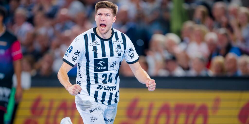 HANDBALL 2025/26: THW Kiel - HSG Wetzlar Ein männlicher Handballspieler in einem schwarz-weiß gestreiften Trikot jubelt leidenschaftlich auf dem Spielfeld, während im Hintergrund eine unscharfe Menschenmenge zusieht.