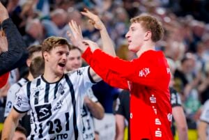 Zwei männliche Sportler feiern enthusiastisch während eines Spiels der THW Kiel Handball-Bundesliga Saison 2025/2026. Der eine in Rot hebt die Hände zum High-Five mit dem schwarz-weiß gestreiften Spieler, während die Menge im Hintergrund Petter Överbys Abschied bejubelt.