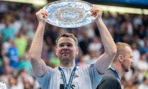 Ein männlicher Sportler im weißen Trikot des THW Kiel hält lächelnd eine große silberne Trophäenplatte über seinen Kopf. Er hat eine Medaille um den Hals und feiert mit den Zuschauern während der Handball-Bundesliga Saison 2025/2026 und Petter Överbys Abschied.
