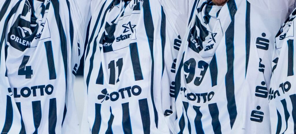 Nahaufnahme von drei Personen, die schwarz-weiß gestreifte Sporttrikots tragen, auf denen die Nummern 4, 11 und 93 sowie verschiedene Sponsorenlogos, darunter Lotto, zu sehen sind. Gesichter und Köpfe sind nicht zu erkennen.