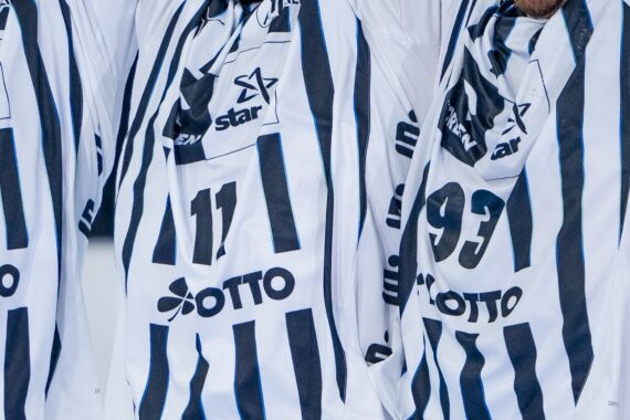 Nahaufnahme von drei Personen, die schwarz-weiß gestreifte Sporttrikots tragen, auf denen die Nummern 4, 11 und 93 sowie verschiedene Sponsorenlogos, darunter Lotto, zu sehen sind. Gesichter und Köpfe sind nicht zu erkennen.