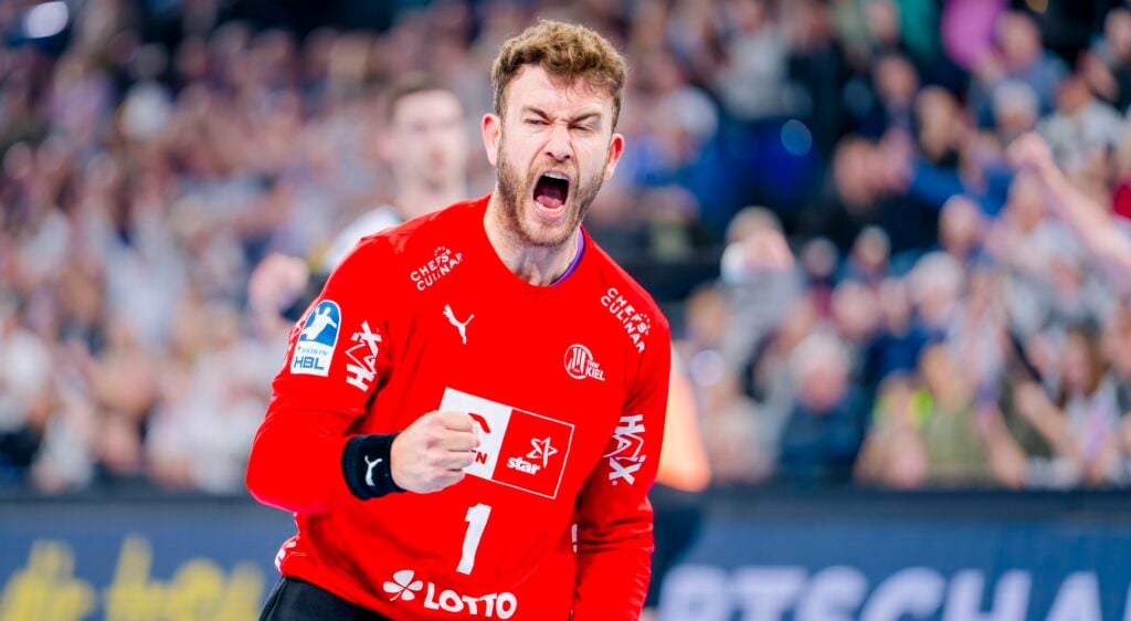 HANDBALL 2025/26: THW Kiel - VfL Gummersbach Ein männlicher Handballspieler in einem roten Trikot jubelt begeistert, ballt die Faust und schreit, während im Hintergrund eine verschwommene Menschenmenge zu sehen ist.