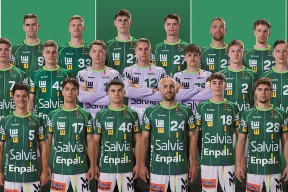 Eine Herren-Volleyballmannschaft in grünen Trikots steht in Reihen zusammen mit Trainern und Betreuern und posiert gemeinsam vor einem grünen Hintergrund.
