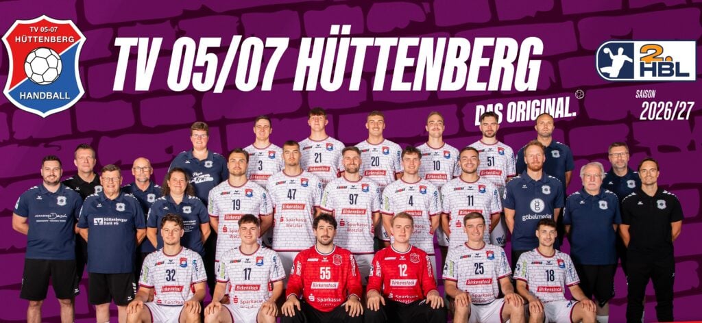 Gruppenfoto der Handballmannschaft und des Stabs von TV 05/07 Hüttenberg in weißen und roten Trikots, posierend vor einem violetten Hintergrund mit dem Mannschaftsnamen und den Logos für die Saison 2026/27 der 2. Handball-Bundesliga.